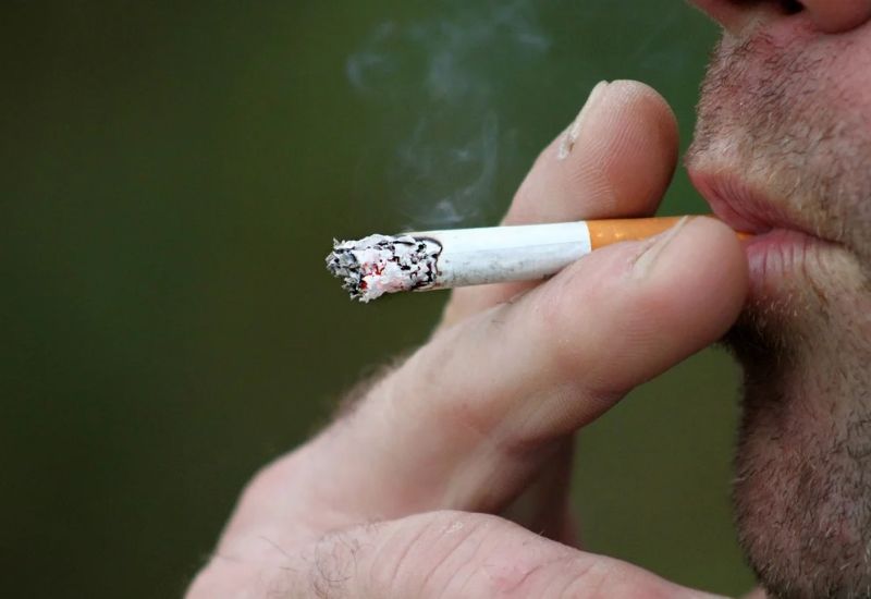 Homem fumando cigarro, representando riscos do tabagismo para o coração.