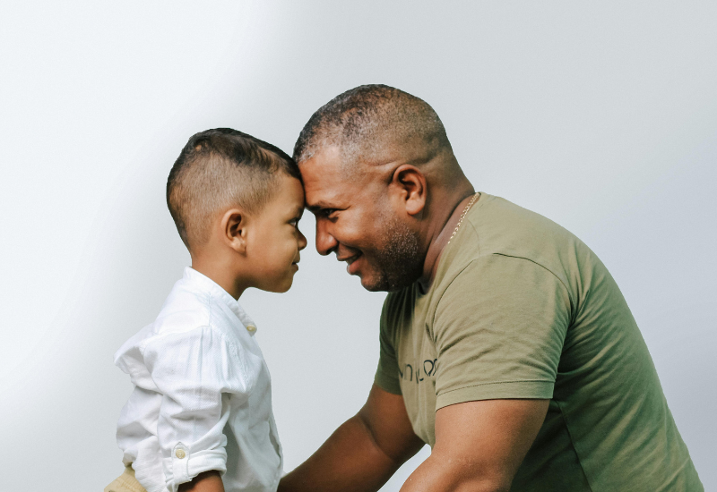 Homem e menino, possivelmente pai e filho, com testa a testa, saúde cardiovascular dos pais.