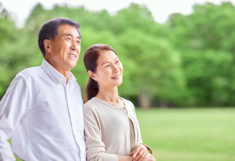Casal de idosos caminhando no parque, desfrutando de momentos ao ar livre com alegria e tranquilidade, representando saúde cardiovascular.