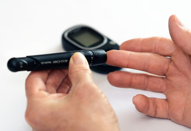 Imagem de alguém durando o dedo para medir a glicemia, representando diabetes e controle glicêmico.